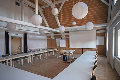 Blick in einen bestuhlten Gruppenraum mit Beamer