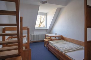 Blick in einen Übernachtungsraum mit zwei Betten und einer Sitzgruppe