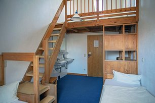 Blick in einen Übernachtungsraum mit Betten, Waschbecken und Treppe